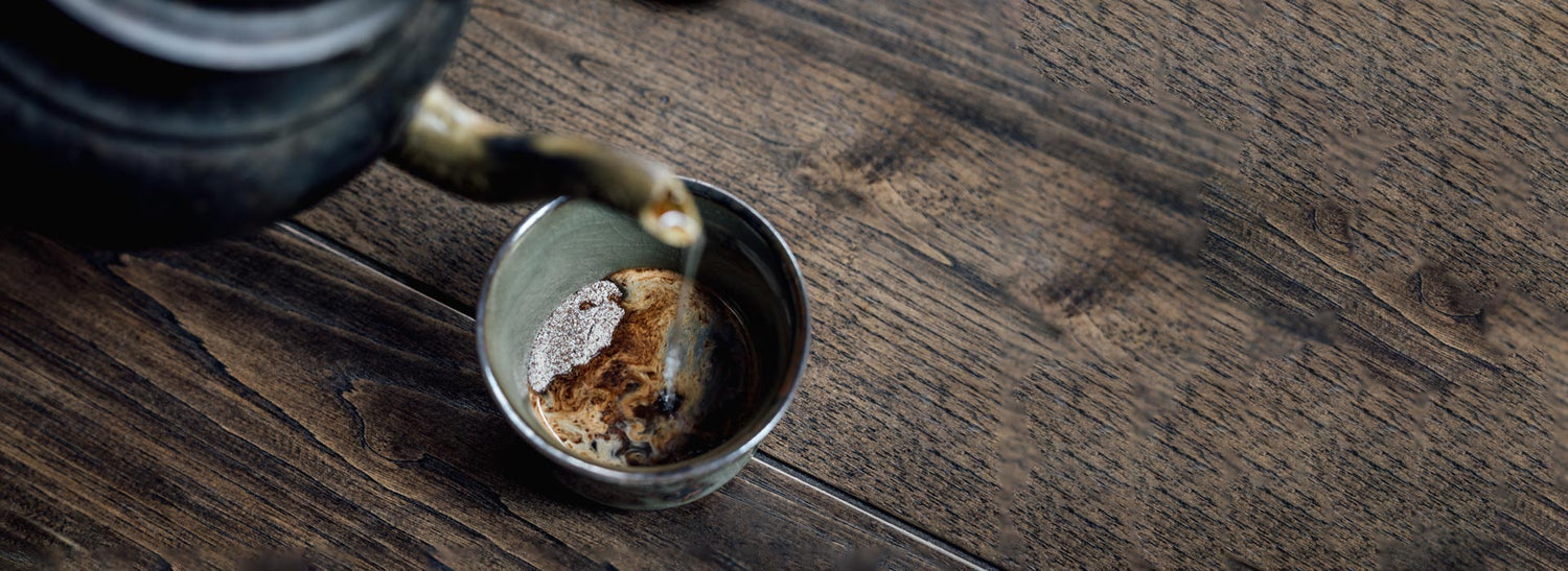 Hot water being poured from a kettle into a cup containing Next Level Boost mushroom coffee powder.